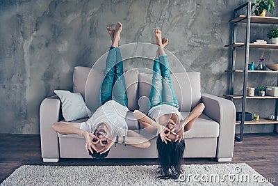 Funny couple with glasses gesturing is lying upside-down on the Stock Photo