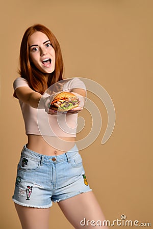 Close up portrait of a hungry young woman eating burger isolated over nude background Stock Photo