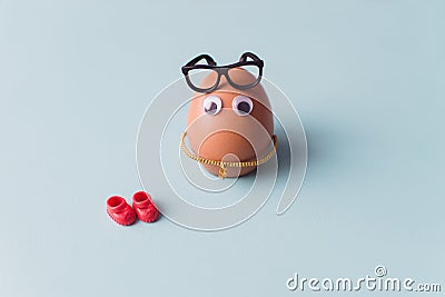 A funny cute brown egg with black glasses and red shoes on blue background Stock Photo