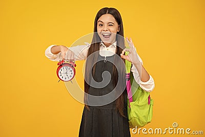 Funny face. Back to school. Teenager school girl with backpack hold clock alarm, time to learn. School children on Stock Photo