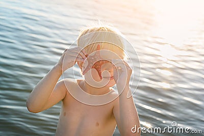 Funny fair-haired child playing with starfish. Seaside holiday with kids Stock Photo