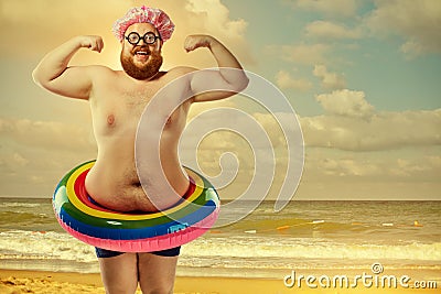 Funny fat man in a swimsuit with an inflatable circle on the bea Stock Photo