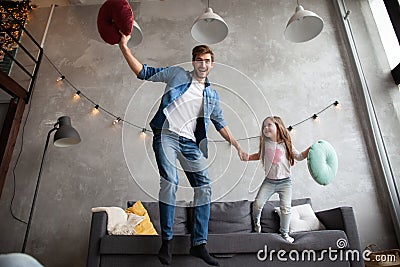 Funny father and cute kid daughter laughing jumping having fun in living room, active family enjoying moving playing Stock Photo