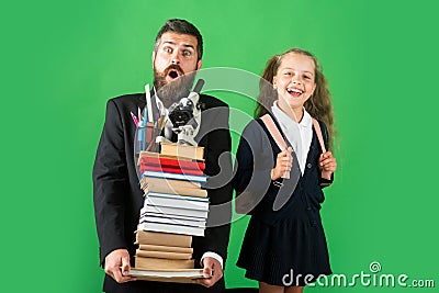 Funny father or teacher with school girl daughter hold big stack school textbook notebook books, isolated on green. Stock Photo