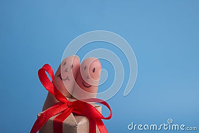 Funny fingers couple holding present gift box against blue background. Happy family celebrating concept for Christmas or New Years Stock Photo