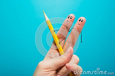 Funny fingers drawing holding yellow pencil against blue background. Conceptual motivation picture Stock Photo