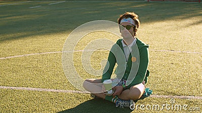 Funny freak sitting on the tennis court and drinking tea Stock Photo