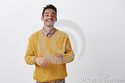 Funny friend tells hilarious jokes. Indoor shot of pleased happy african-american in stylish outfit smiling broadly and Stock Photo