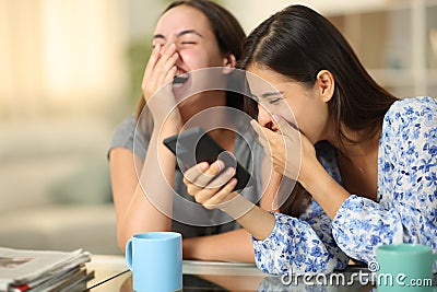 Funny friends watching media on phone laughing loud Stock Photo