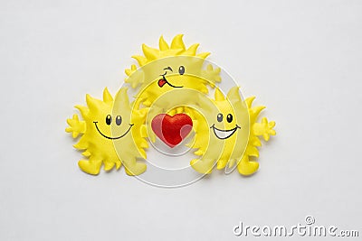 Funny flock of smiling holiday toy sun with a red heart on a white background Stock Photo