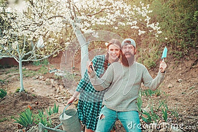 Funny gardener couple holding garden tools at spring nature background. Couple of Gardeners with garden tools. Portrait Stock Photo