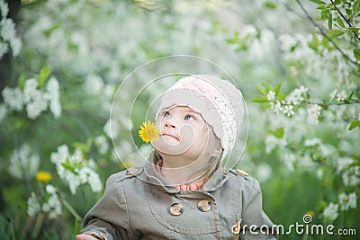 Funny girl with Down syndrome in the mouth pulls dandelions Stock Photo