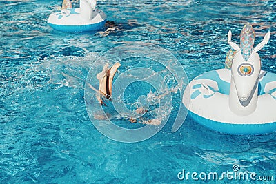 Funny girl dropped fell from inflatable ring unicorn. Kid child enjoying having fun in swimming pool. Summer outdoor water Stock Photo