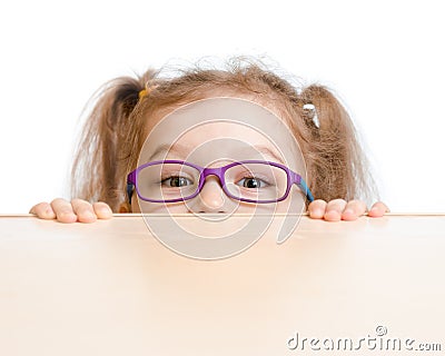 Funny girl in eyeglasses hiding behind table Stock Photo