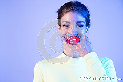 Funny girl with full fake lips on neon background. Stock Photo