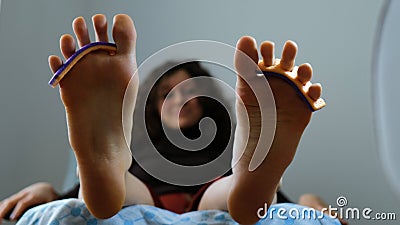 Funny girl shakes feet with dividers for fingers in a pedicure chair in a beauty salon Stock Photo