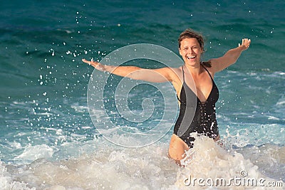 Funny girl in swimsuit is swimming in sea water. Woman splashing in sea waves and drops Stock Photo