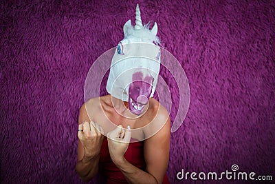 Funny girl unicorn ready to fight and clenches fists. Freaky young woman Stock Photo