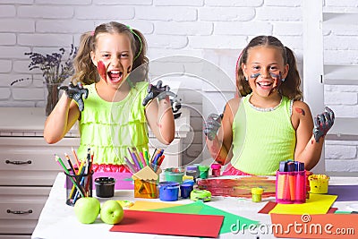 Funny girls children painters painting with gouache paints on table. Happy smiling kids with colored hands. Arts and Stock Photo