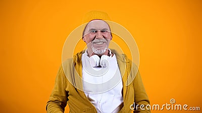 Funny grandfather in headphones and casual clothes smiling at camera, happy dj Stock Photo