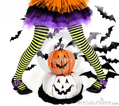Funny green black Striped legs of a little girl with halloween costume of a witch with witch shoes and smiley halloween pumpkin Stock Photo