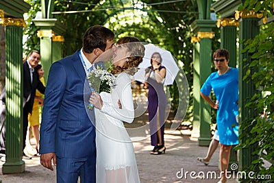 Funny groom kissing bride in wedding dress under the arch Stock Photo