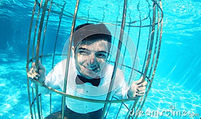 Funny groom underwater in a bird cage Stock Photo