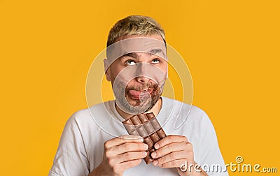Funny guy eats chocolate and rolls his eyes Stock Photo