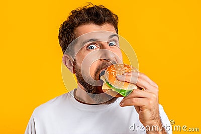 funny guy satisfying food cravings with cheeseburger on yellow background Stock Photo