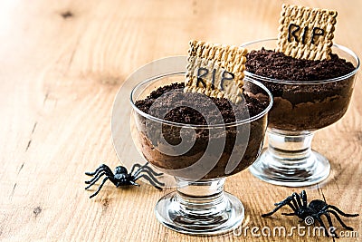 Funny Halloween chocolate mousse with tomb cookie and spiders on wood Stock Photo