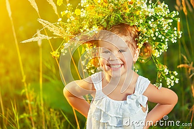 funny happy baby child girl in a wreath on nature laughing in summer Stock Photo