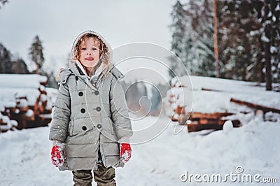 Funny happy child girl portrait on the walk in winter snowy forest with tree felling on background Stock Photo