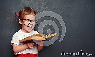 Funny happy girl schoolgirl with book from blackboard Stock Photo