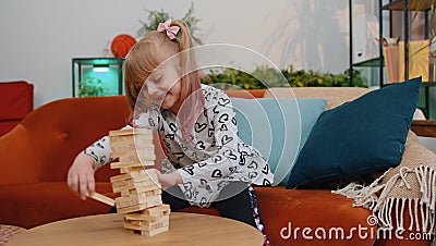 Funny happy one teenage kid girl play wooden tower blocks bricks game at home in modern living room Stock Photo