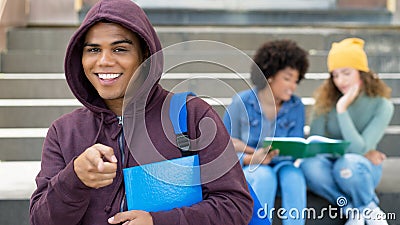 Funny hispanic male student with hoody and group of caucasian and african american young adults Stock Photo