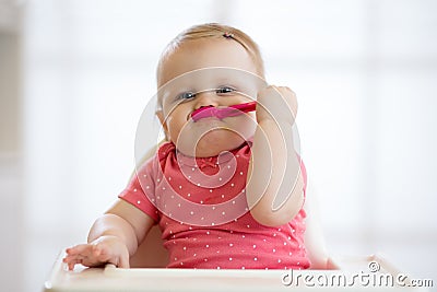 Funny infant baby spoon eats itself Stock Photo