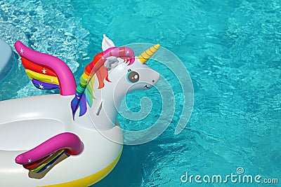 Funny inflatable unicorn ring floating in swimming pool on sunny day Stock Photo