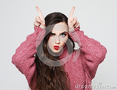 Funny joking young woman, feels happy, makes horns on her head with fingers Stock Photo