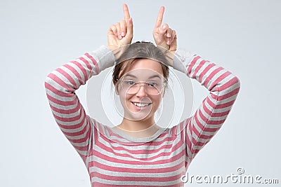 Funny joking young woman making horns with fingers Stock Photo