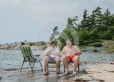 Funny joyful friends talking laughing relaxing in park near the lake Stock Photo