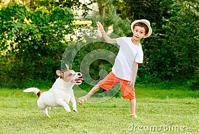 Funny kid boy throws stick to his dog playing fetch game Stock Photo