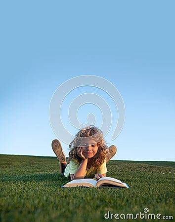 Funny kid reading the book in spring park. Child boy with a book in the garden. Kid is readding a book playing outdoors Stock Photo