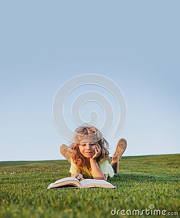 Funny kid reading the book in spring park. Child boy with a book in the garden. Kid is readding a book playing outdoors Stock Photo