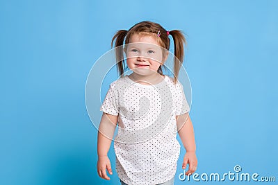 Funny kid in white T-shirt on blue background. Little pretty girl isolated on blue background. Copy space for text. Stock Photo