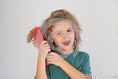 Funny kids hairstyle. Cute child with comb. Blonde kid combs unruly hair. Kid boy with tangled long hair. Stock Photo