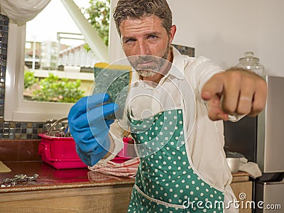 Funny lifestyle portrait of mid adult unhappy and stressed man in kitchen apron feeling frustrated and upset overwhelmed by Stock Photo