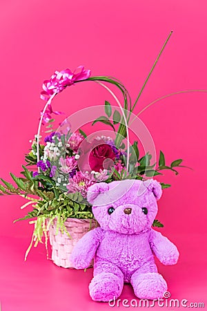 Funny lilac teddy bear with basket of flowers on pink background. Cute greeting postcard Stock Photo