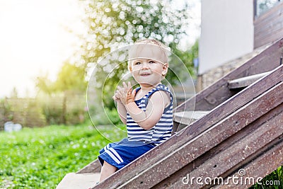 Funny little boy one year, sitting on the porch of a country house. Summer, childhood, nature Stock Photo