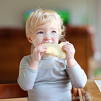 Funny little girl eating sandwich at home Stock Photo