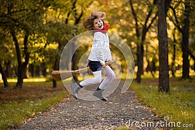 Funny little girl flies on broom in autumn Stock Photo